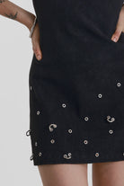 Black ribbed mini dress with slash neck and piercing and stud hardware details, worn by a model