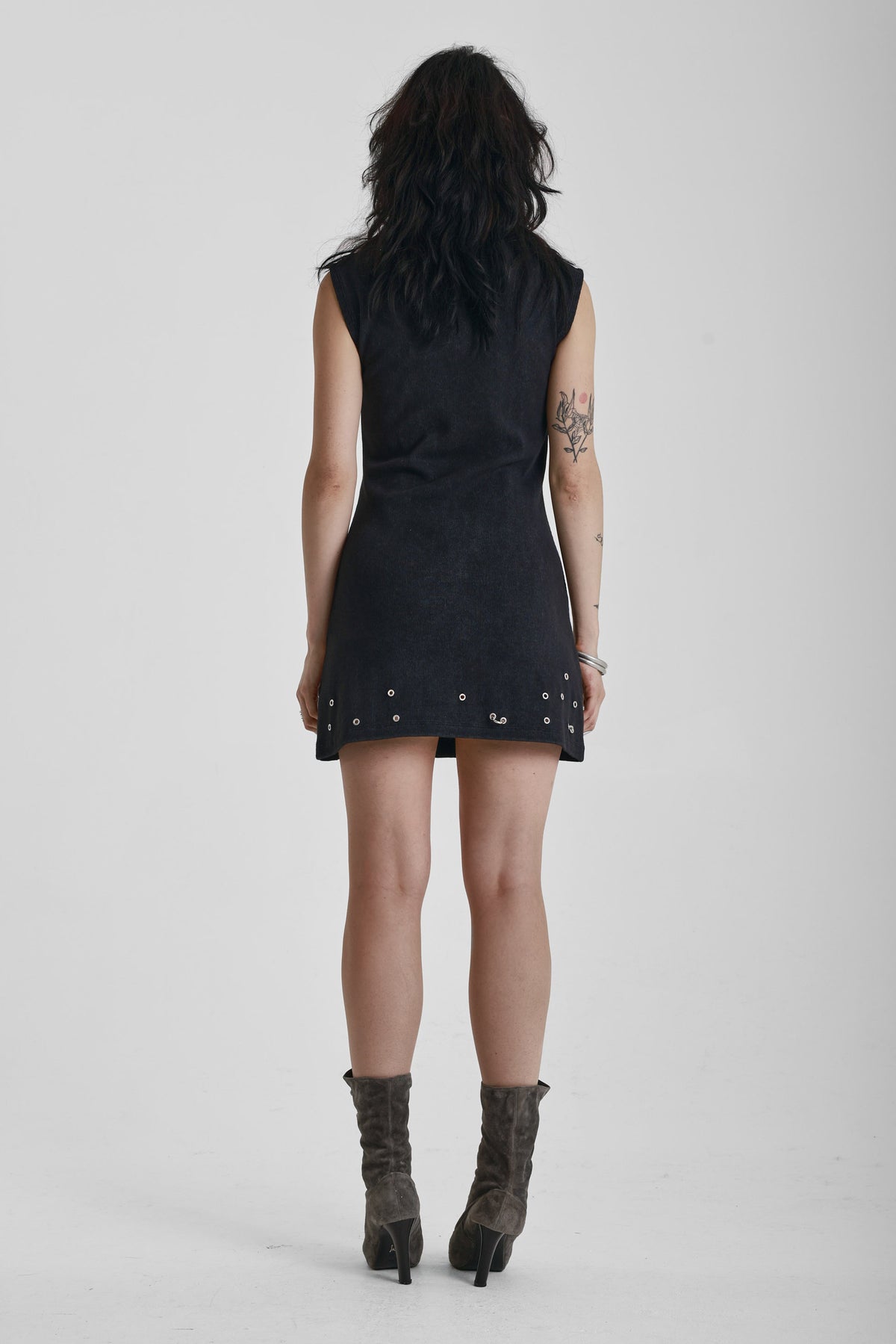 Black ribbed mini dress with slash neck and piercing and stud hardware details, worn by a model
