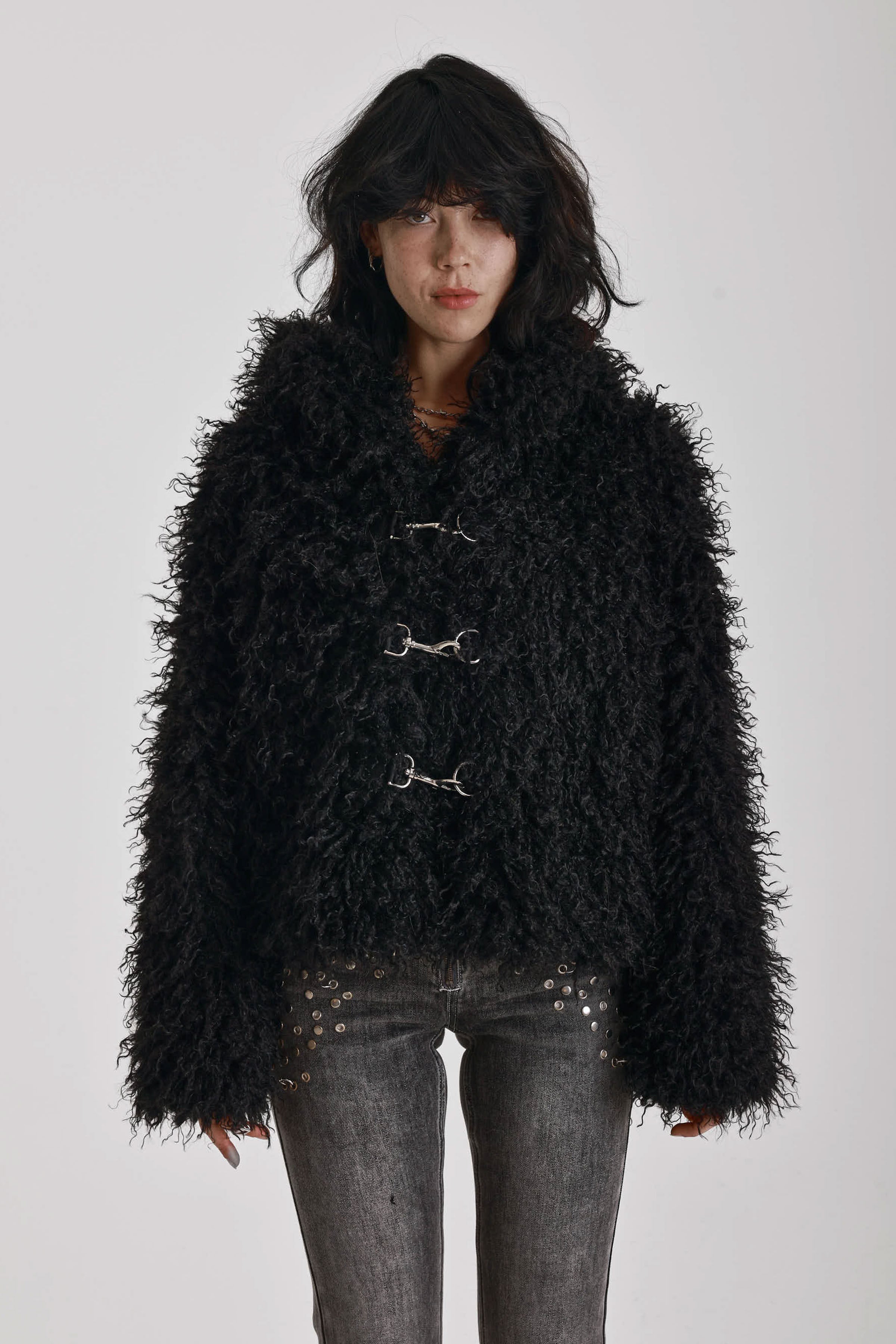 Black shaggy faux fur hooded jacket with silver clasps, worn by model