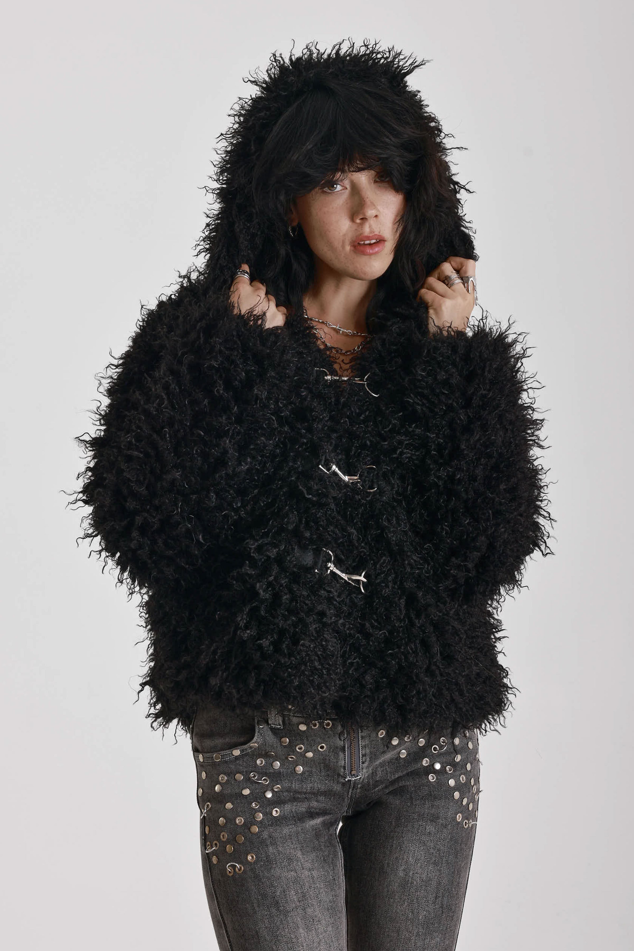 Black shaggy faux fur hooded jacket with silver clasps, worn by model