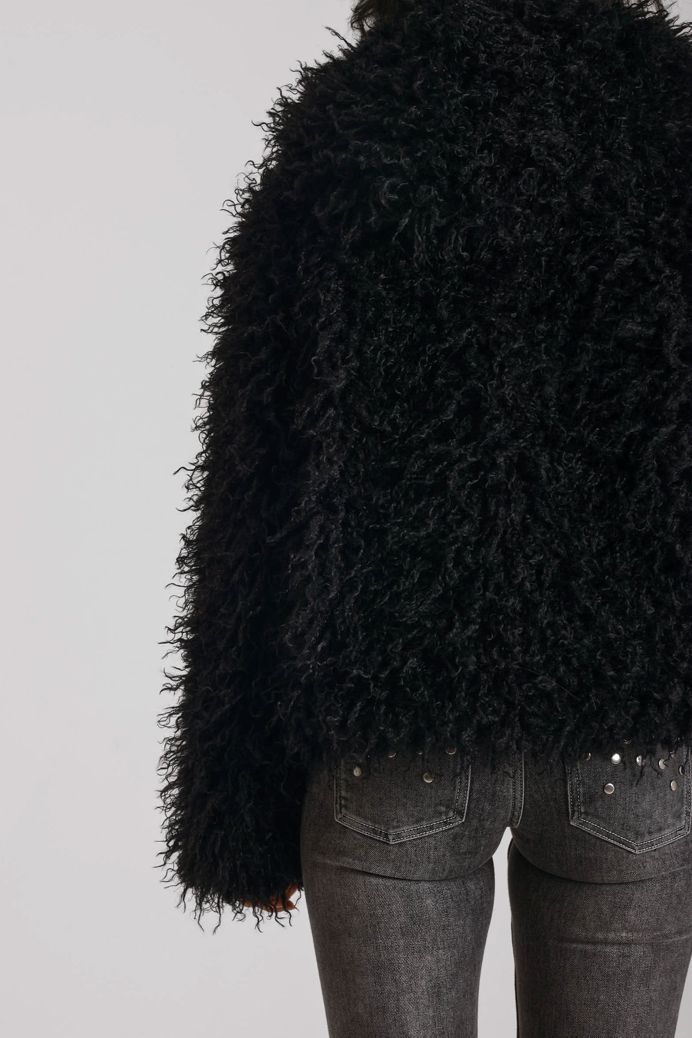 Black shaggy faux fur hooded jacket with silver clasps, worn by model