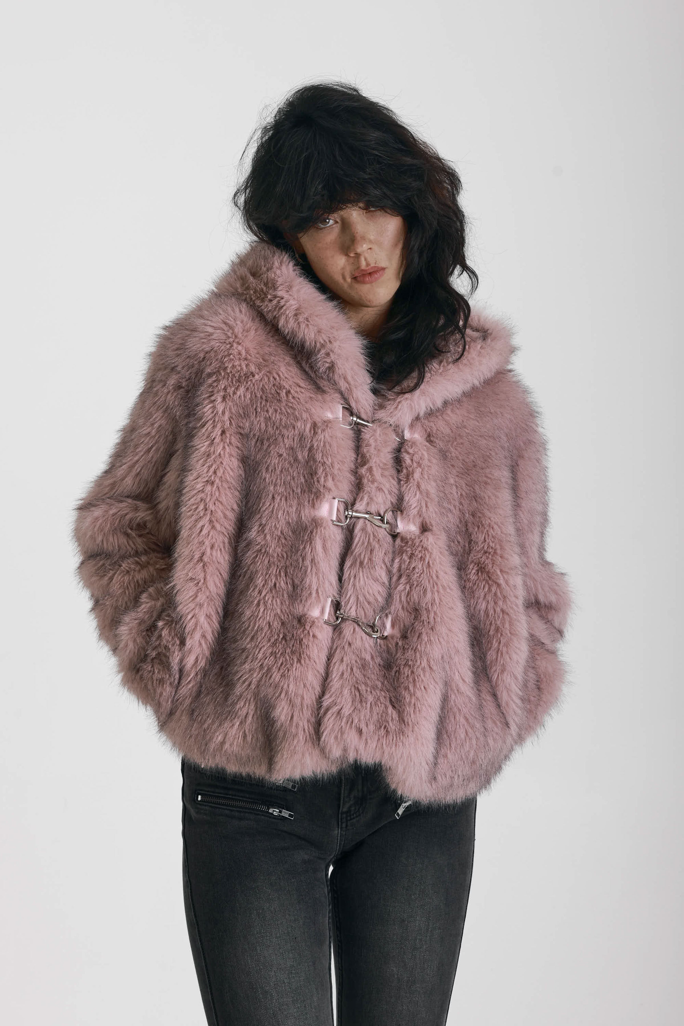 Dusty pink faux fur jacket with silver buckle clasps and a hood, worn by model