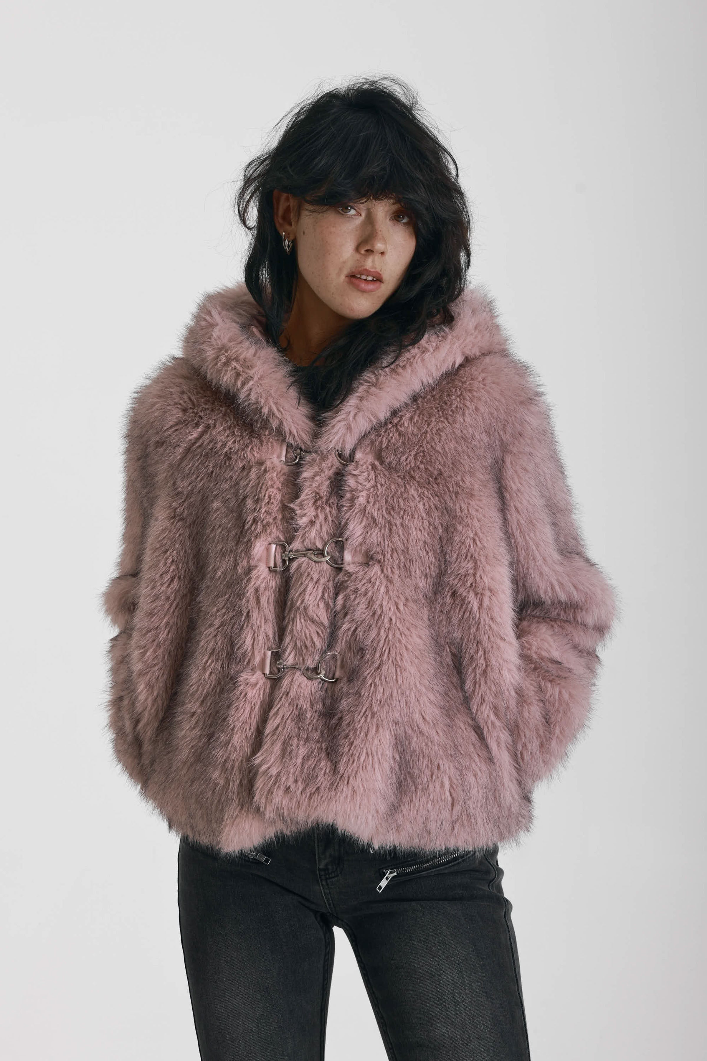 Dusty pink faux fur jacket with silver buckle clasps and a hood, worn by model