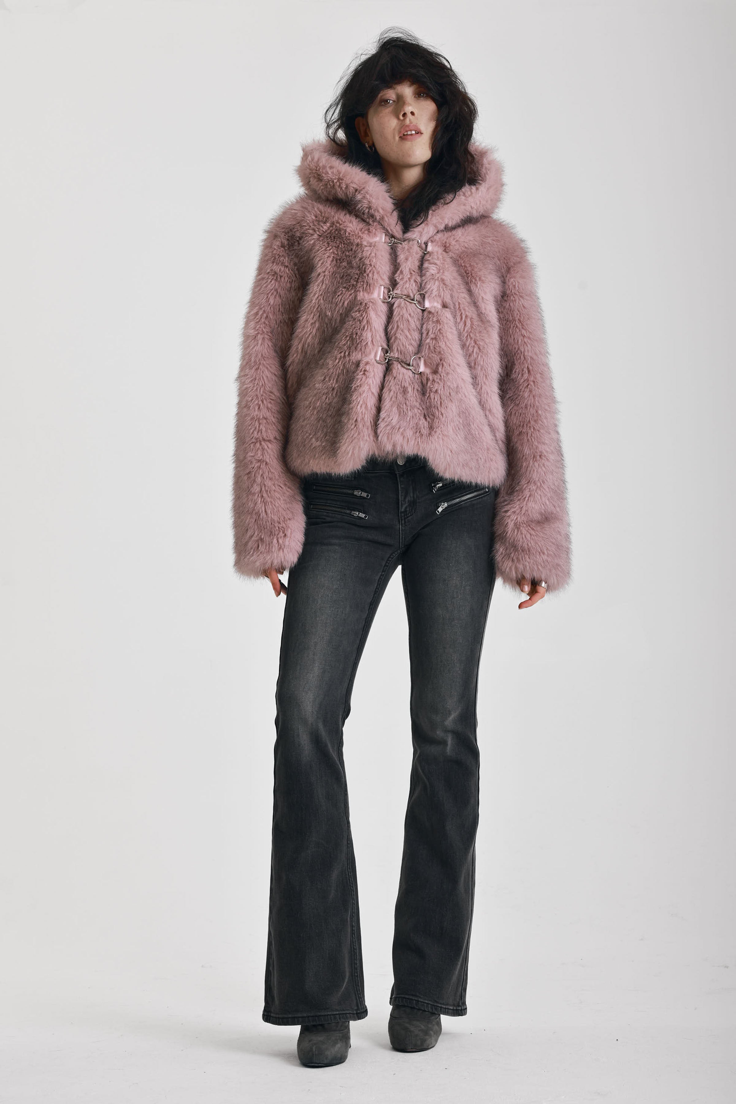 Dusty pink faux fur jacket with silver buckle clasps and a hood, worn by model