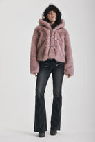 Dusty pink faux fur jacket with silver buckle clasps and a hood, worn by model