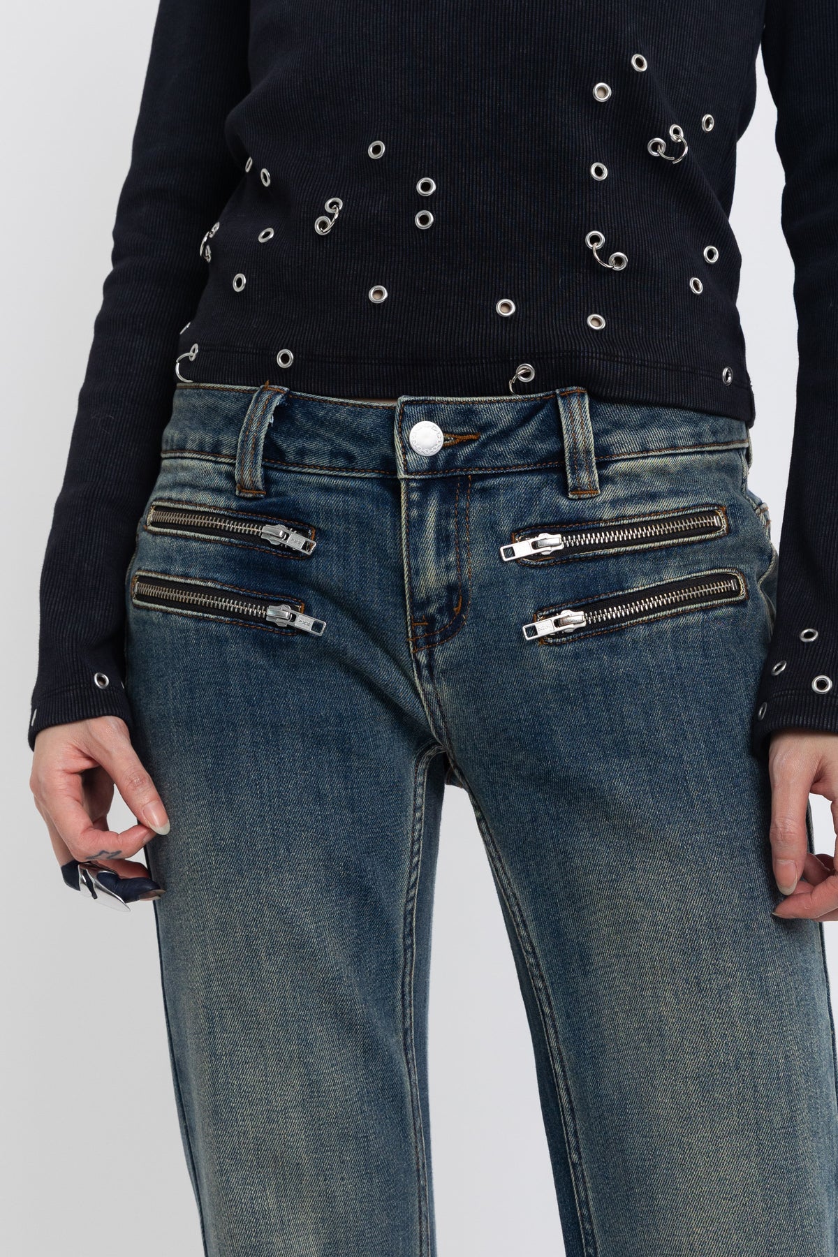 Dirty blue wash low rise flare jeans with double zip hip detail, worn by model