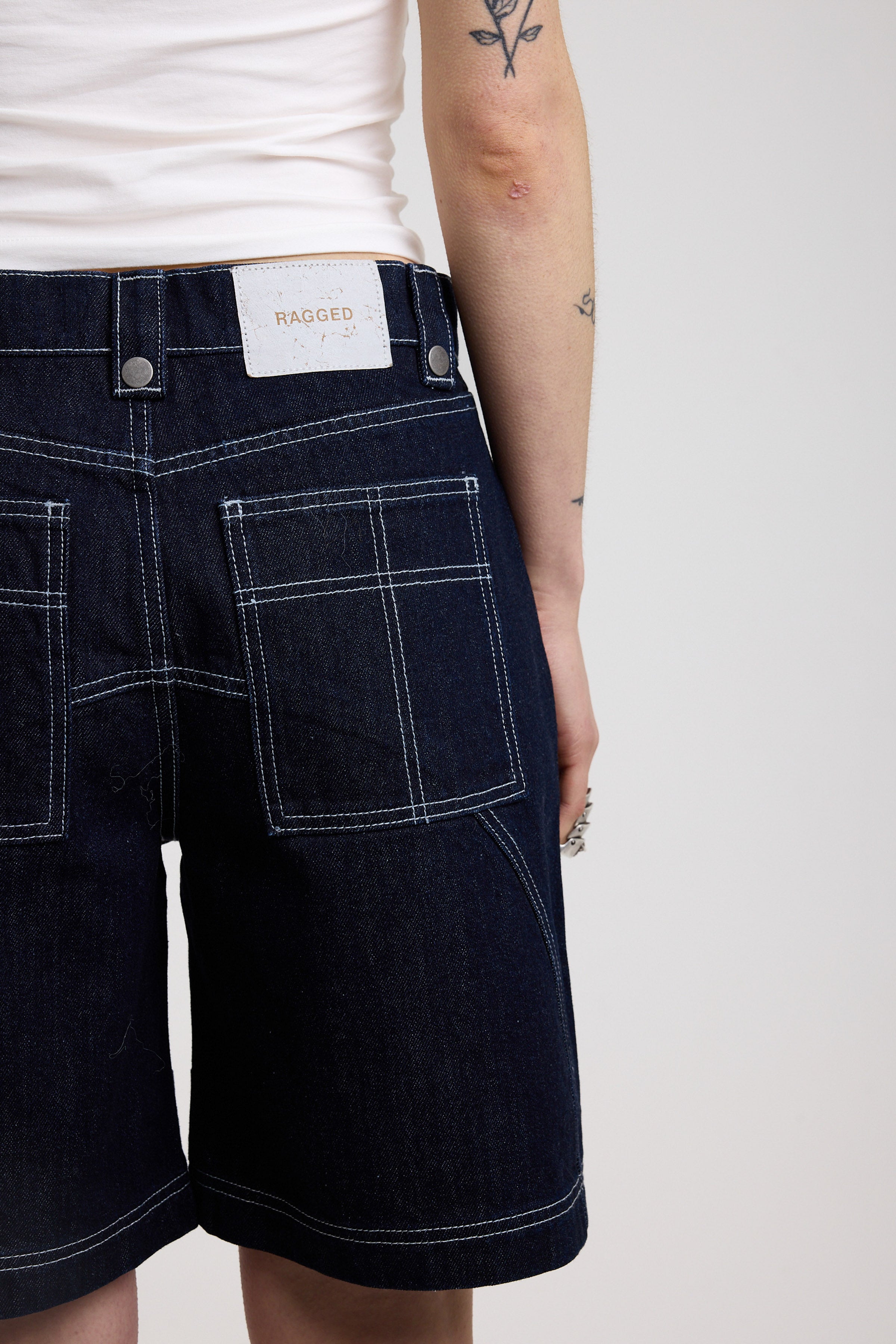 Back detail of dark rinse denim jorts with seam detail and exposed zip, worn by model