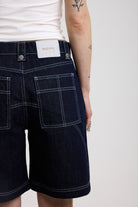 Back detail of dark rinse denim jorts with seam detail and exposed zip, worn by model