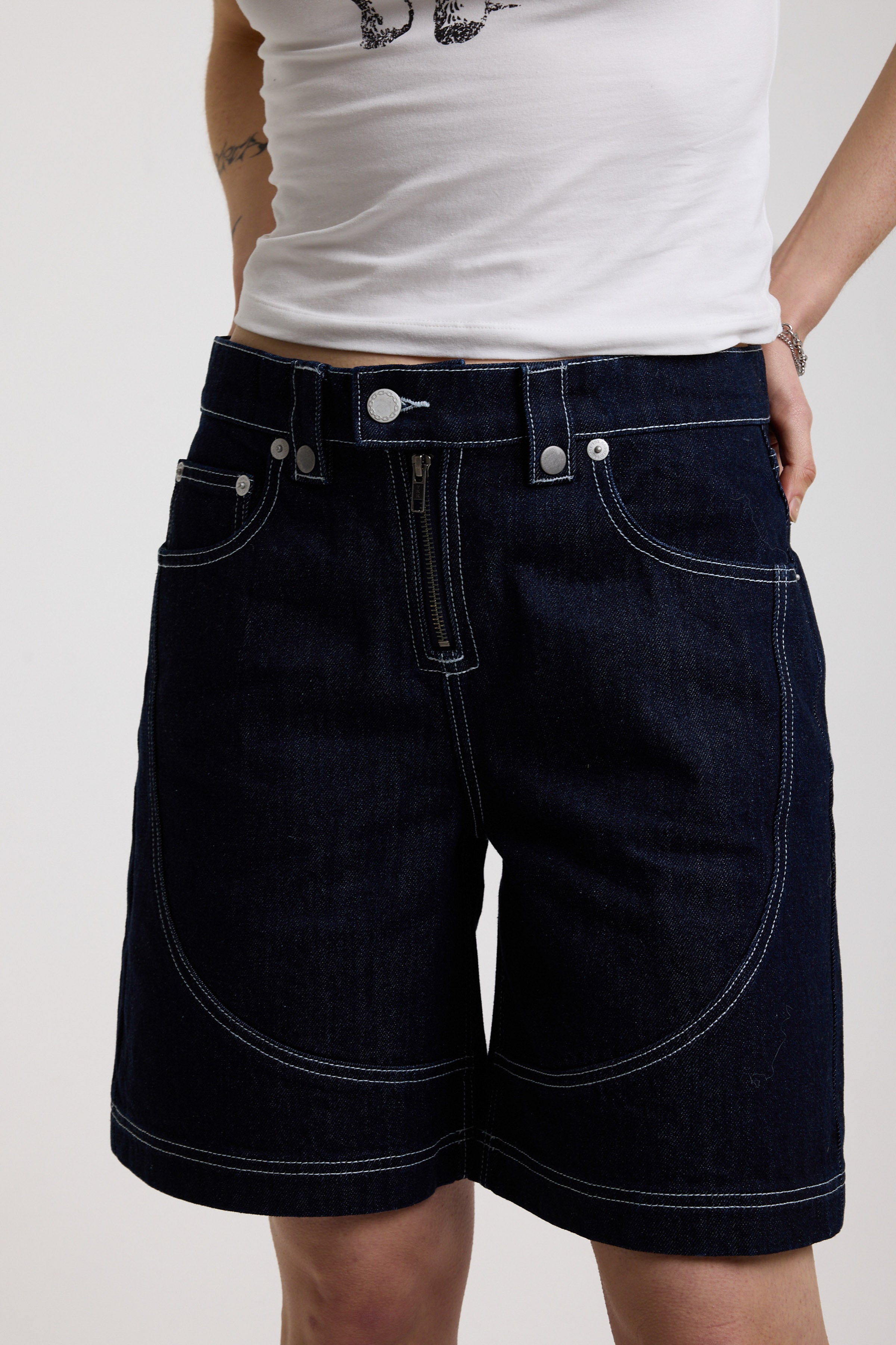 Dark rinse denim jorts with seam detail and exposed zip, worn by model