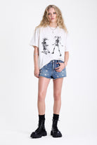 Mid blue denim mini shorts with raw hem and silver eyelet rivet and stud detail, worn by model
