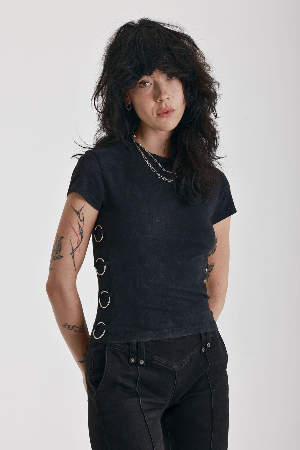 Acid wash black baby t-shirt with short sleeves and silver O-ring hardware, worn by model