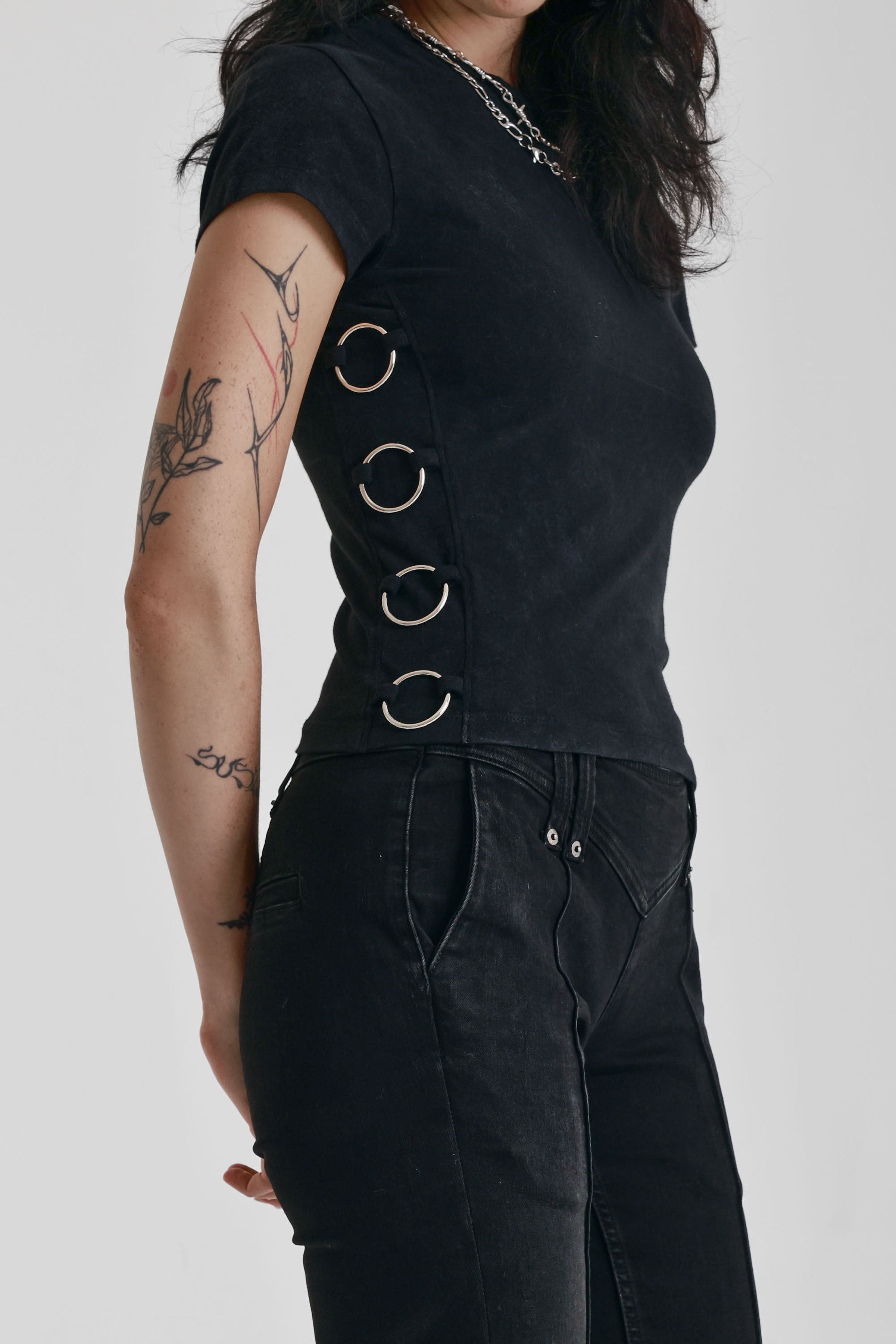 Acid wash black baby t-shirt with short sleeves and silver O-ring hardware, worn by model