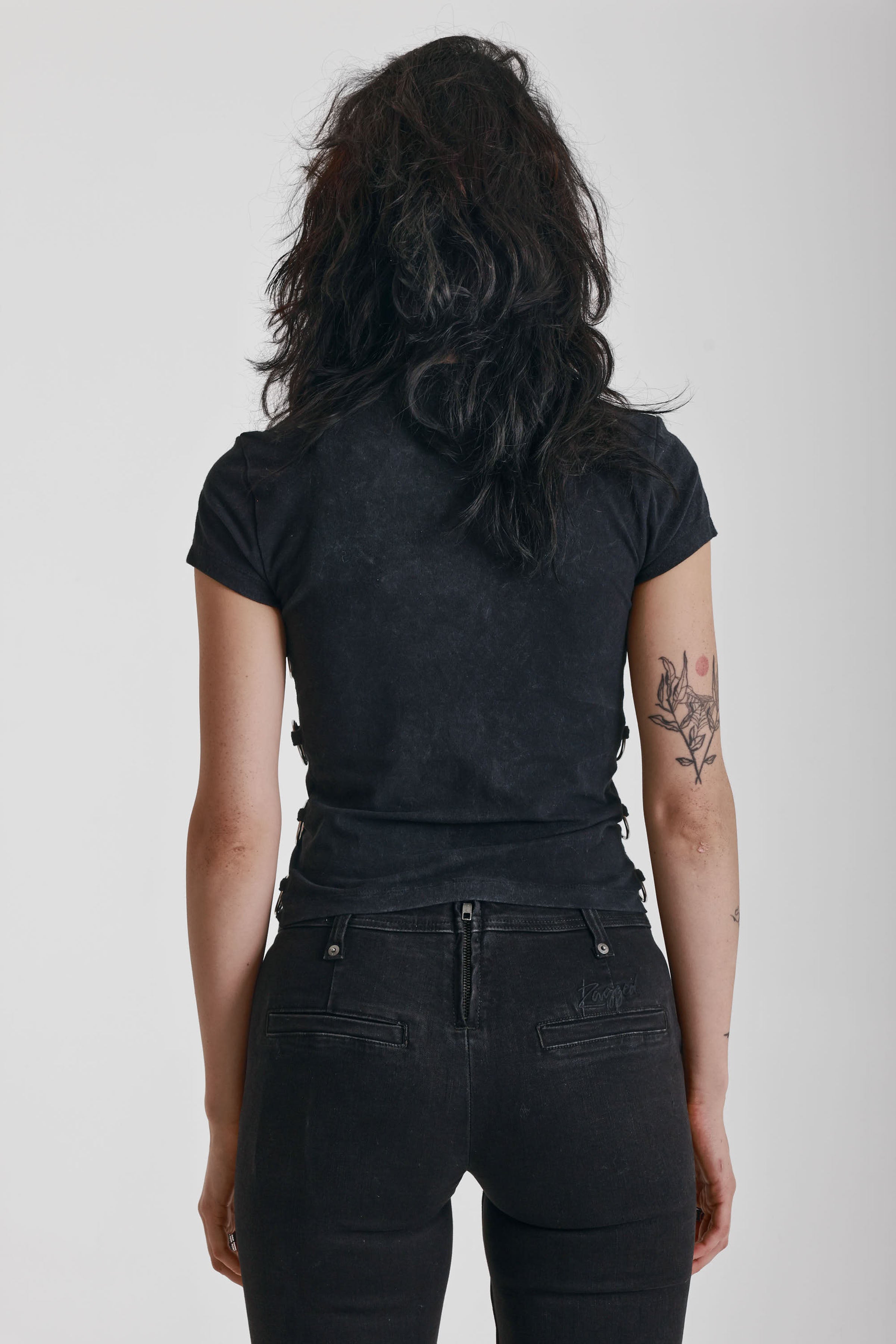 Acid wash black baby t-shirt with short sleeves and silver O-ring hardware, worn by model
