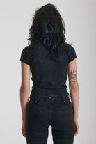 Acid wash black baby t-shirt with short sleeves and silver O-ring hardware, worn by model