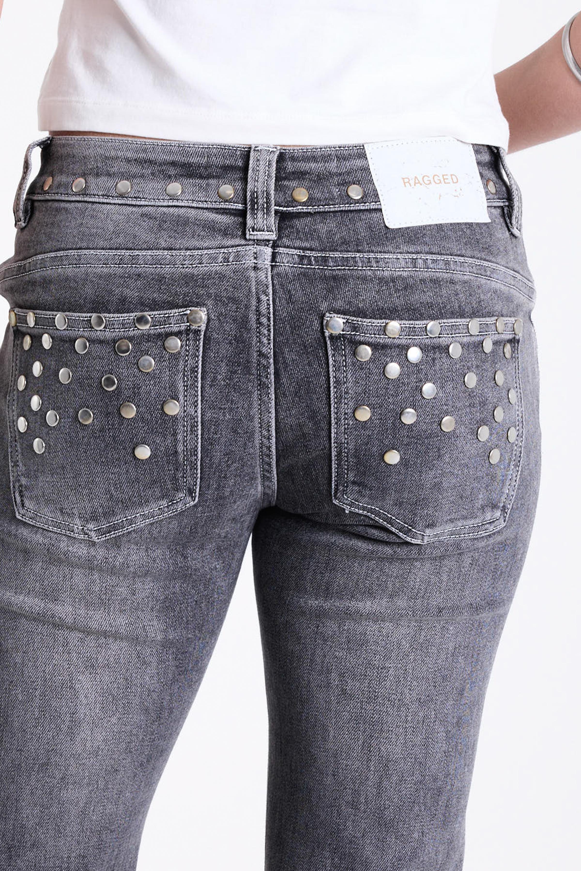 Washed grey low rise flare jeans with exposed front zip and silver stud and piercing hardware, worn by model.