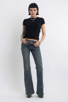 Vintage wash low rise flare jeans with eyelet and horsebit clasp belt, worn by model