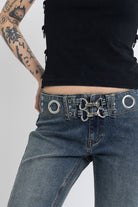 Vintage wash low rise flare jeans with eyelet and horsebit clasp belt, worn by model