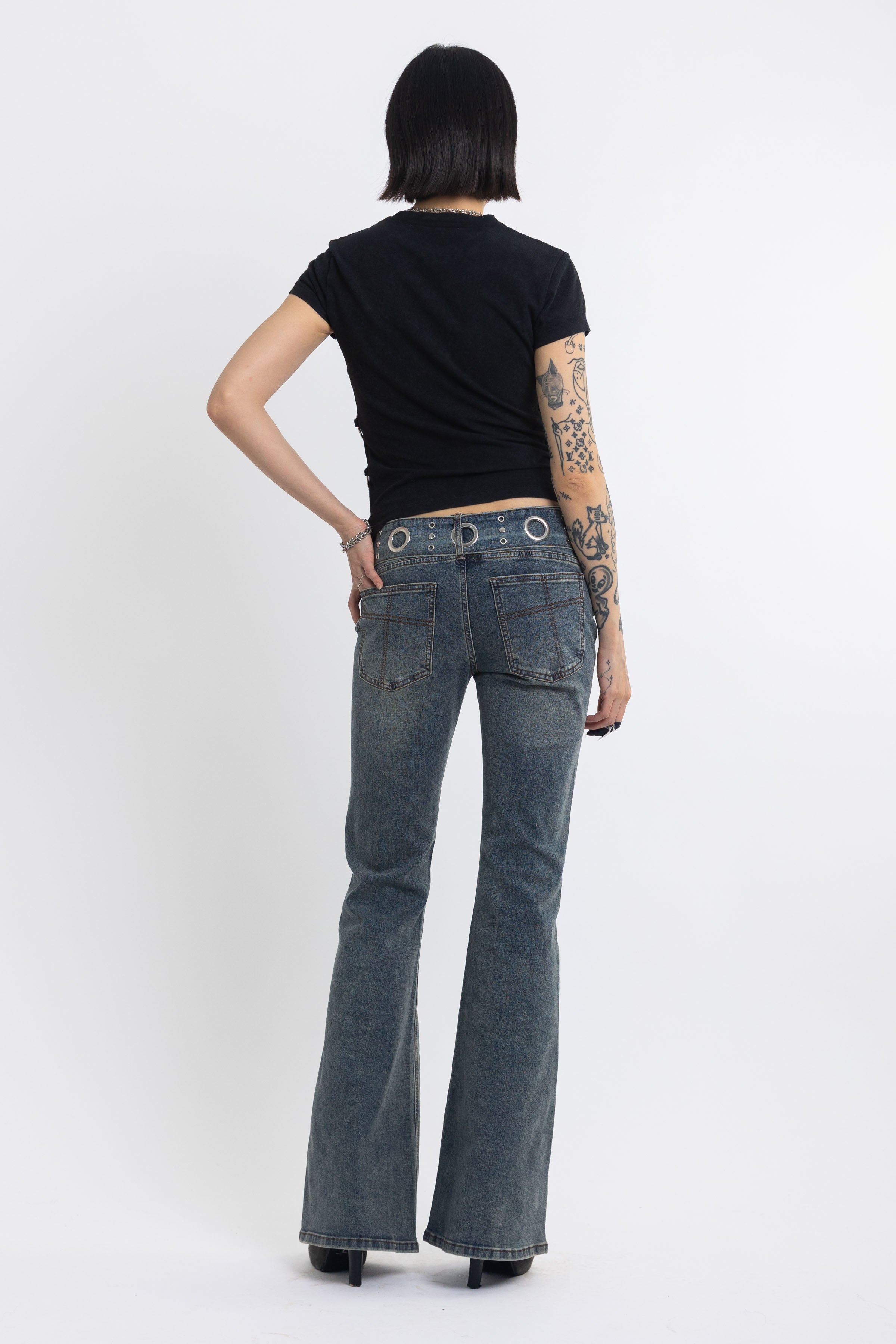 Vintage wash low rise flare jeans with eyelet and horsebit clasp belt, worn by model