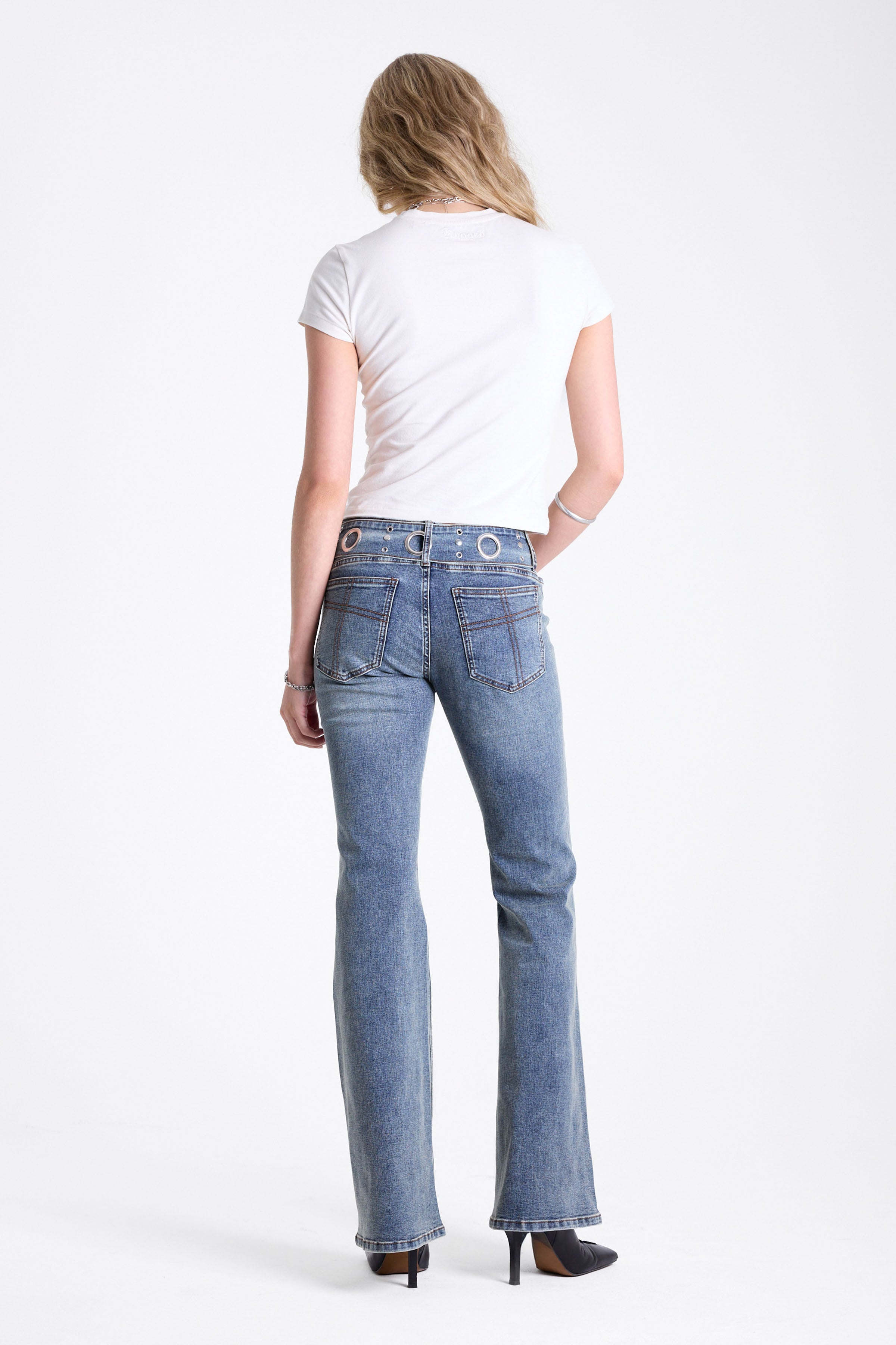 Vintage wash low rise flare jeans with oversized eyelet buckle belt, worn by mdoel