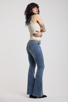 Back image of blue flare bootcut jeans with double buckle belt detail, worn by model