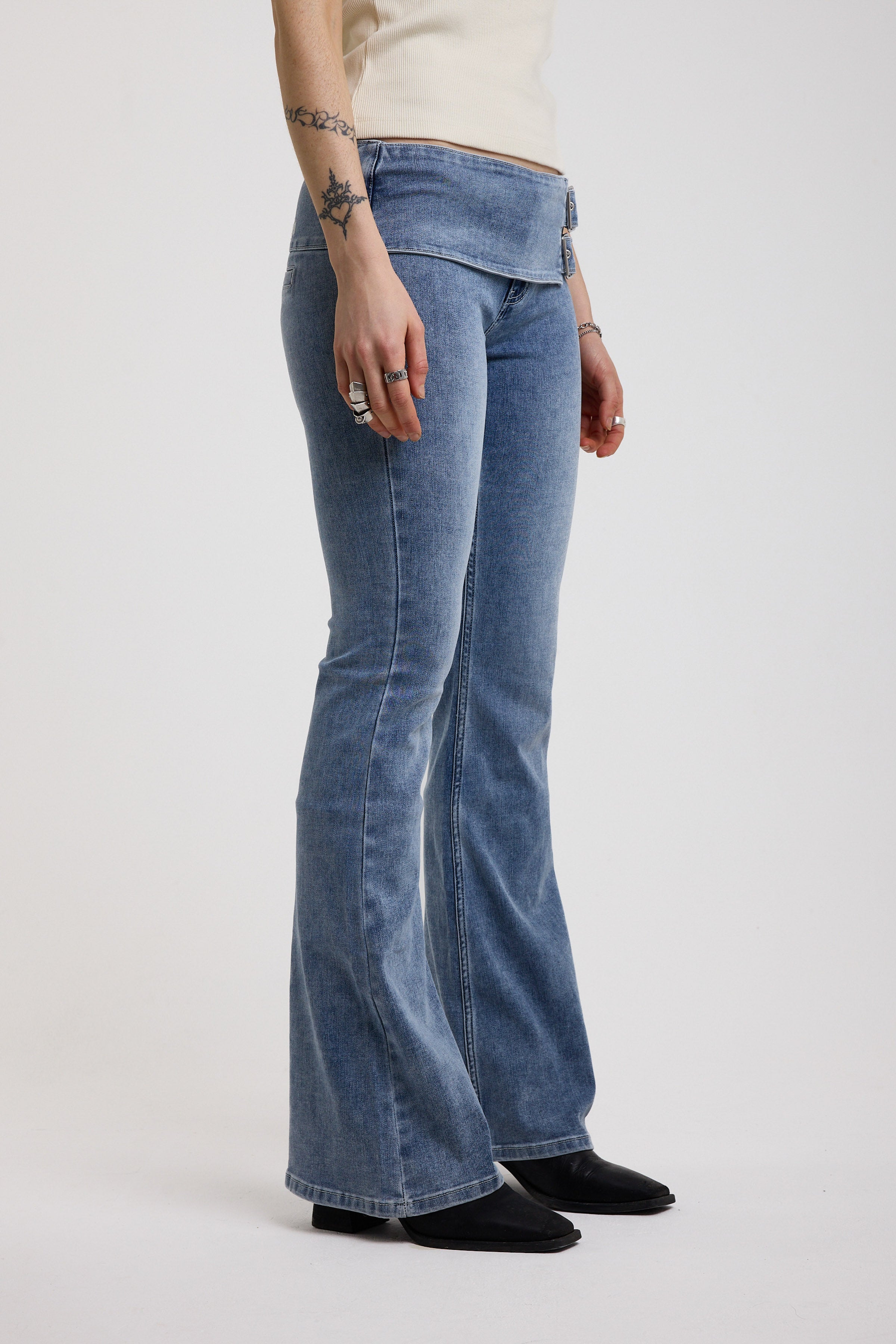 Blue flare bootcut jeans with double buckle belt detail, worn by model