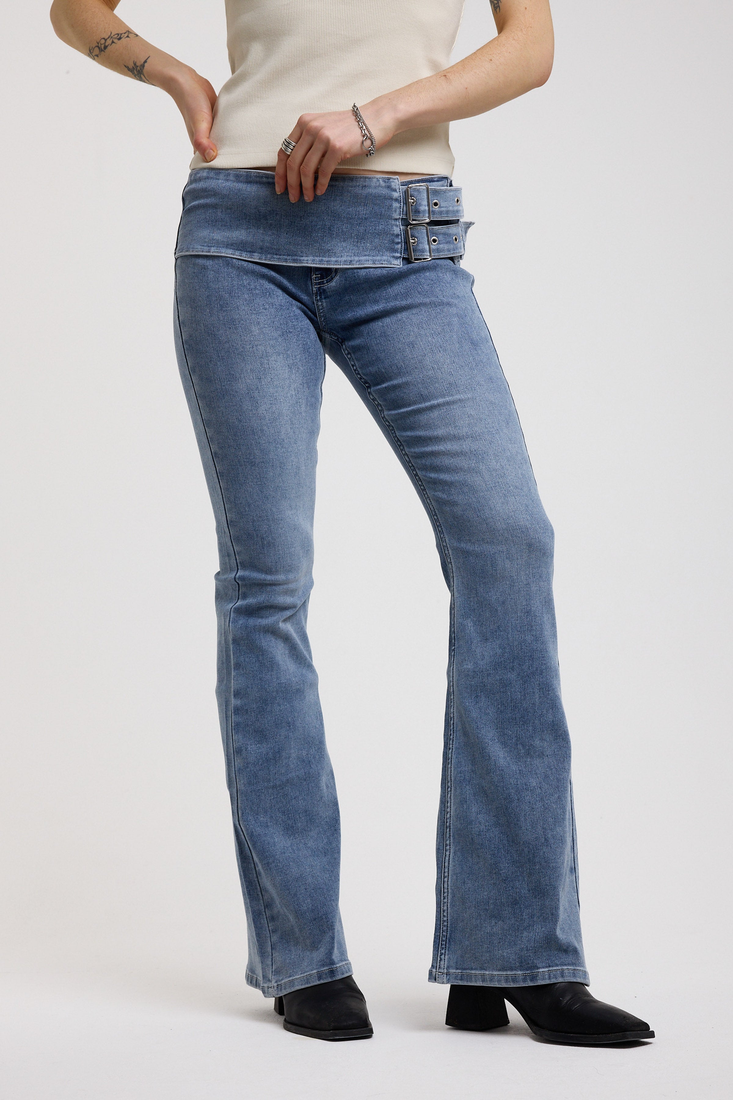 Blue flare bootcut jeans with double buckle belt detail, worn by model