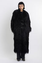 Longline black shaggy faux fur coat with silver horsebit clasps and shawl collar, worn by model