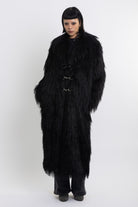 Longline black shaggy faux fur coat with silver horsebit clasps and shawl collar, worn by model