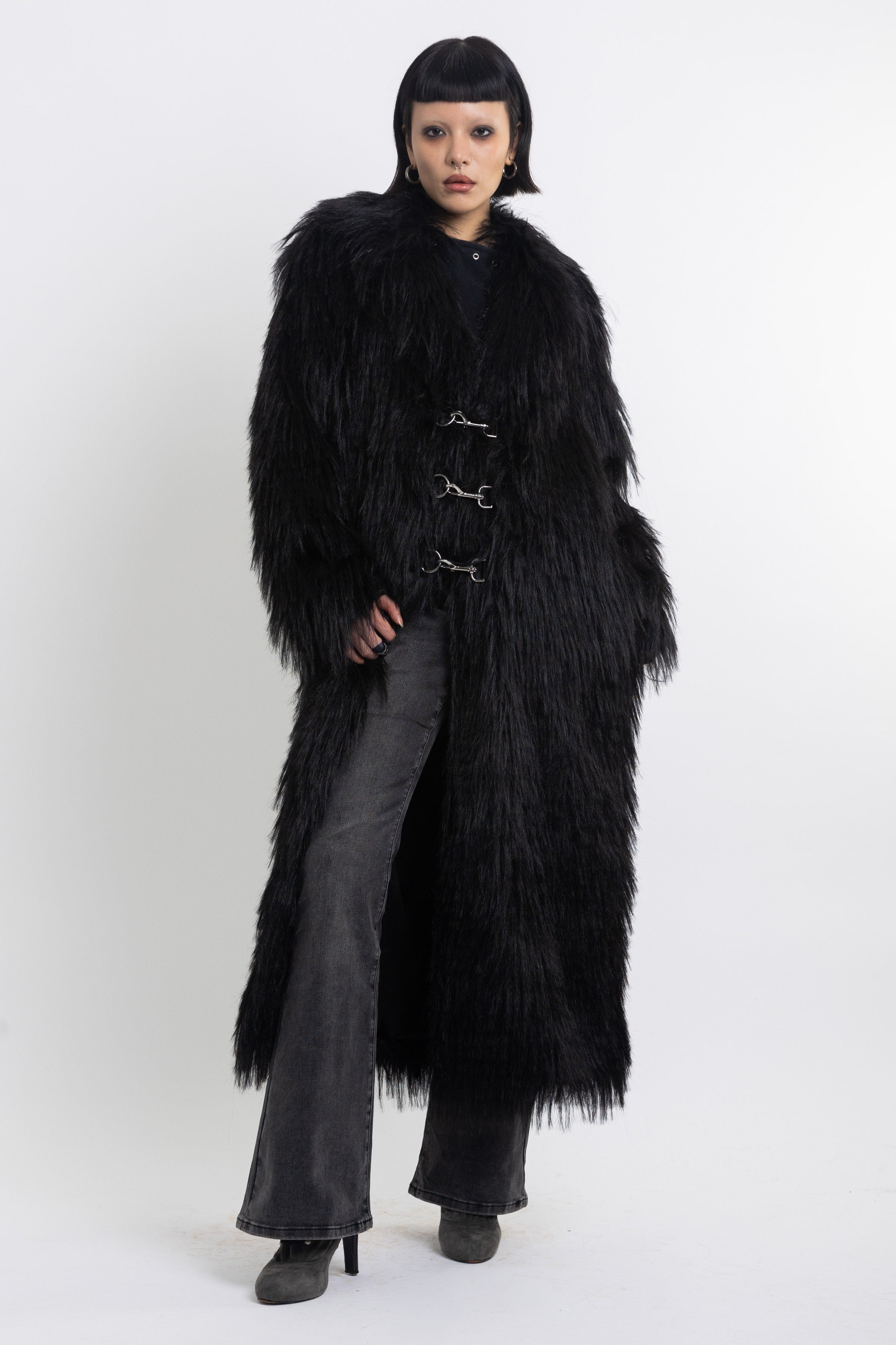 Longline black shaggy faux fur coat with silver horsebit clasps and shawl collar, worn by model