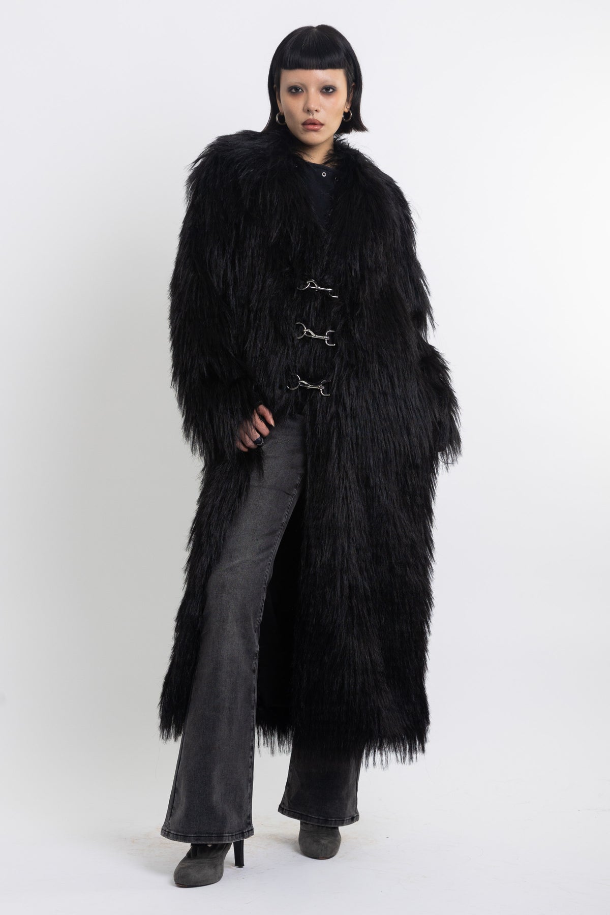 Longline black shaggy faux fur coat with silver horsebit clasps and shawl collar, worn by model