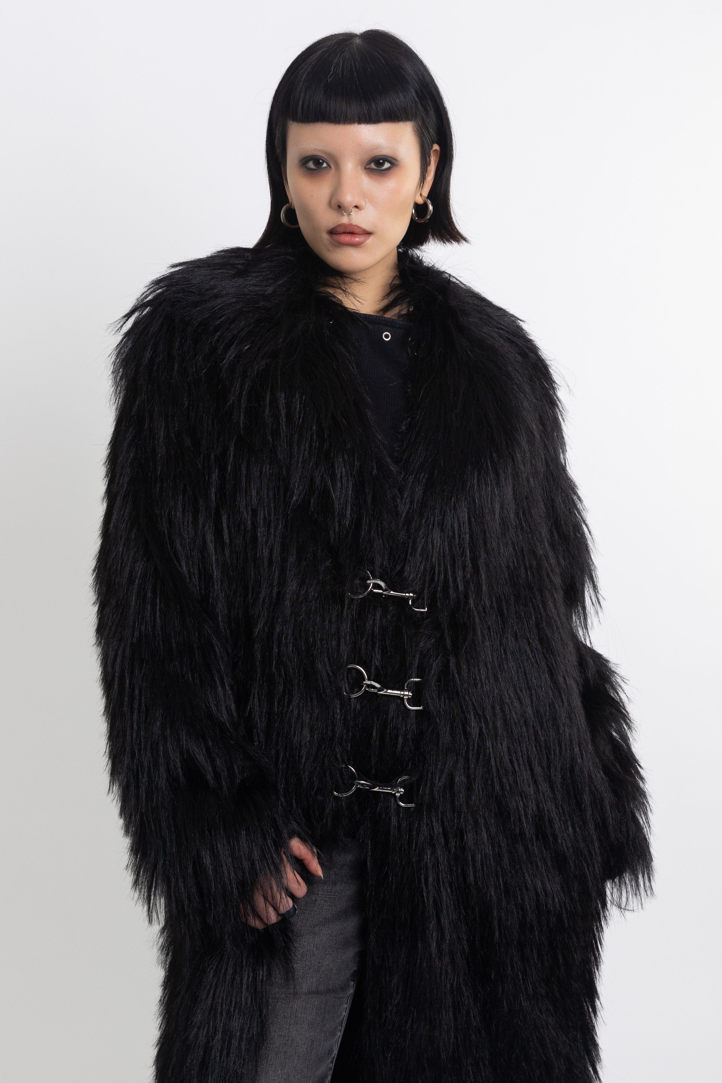 Longline black shaggy faux fur coat with silver horsebit clasps and shawl collar, worn by model