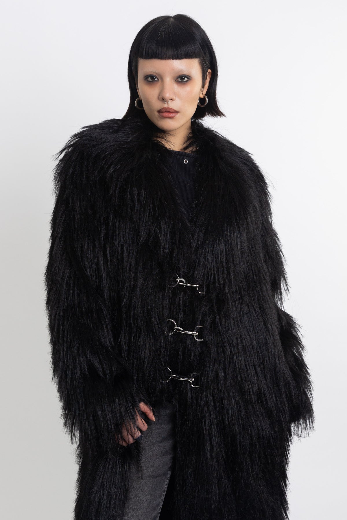 Longline black shaggy faux fur coat with silver horsebit clasps and shawl collar, worn by model