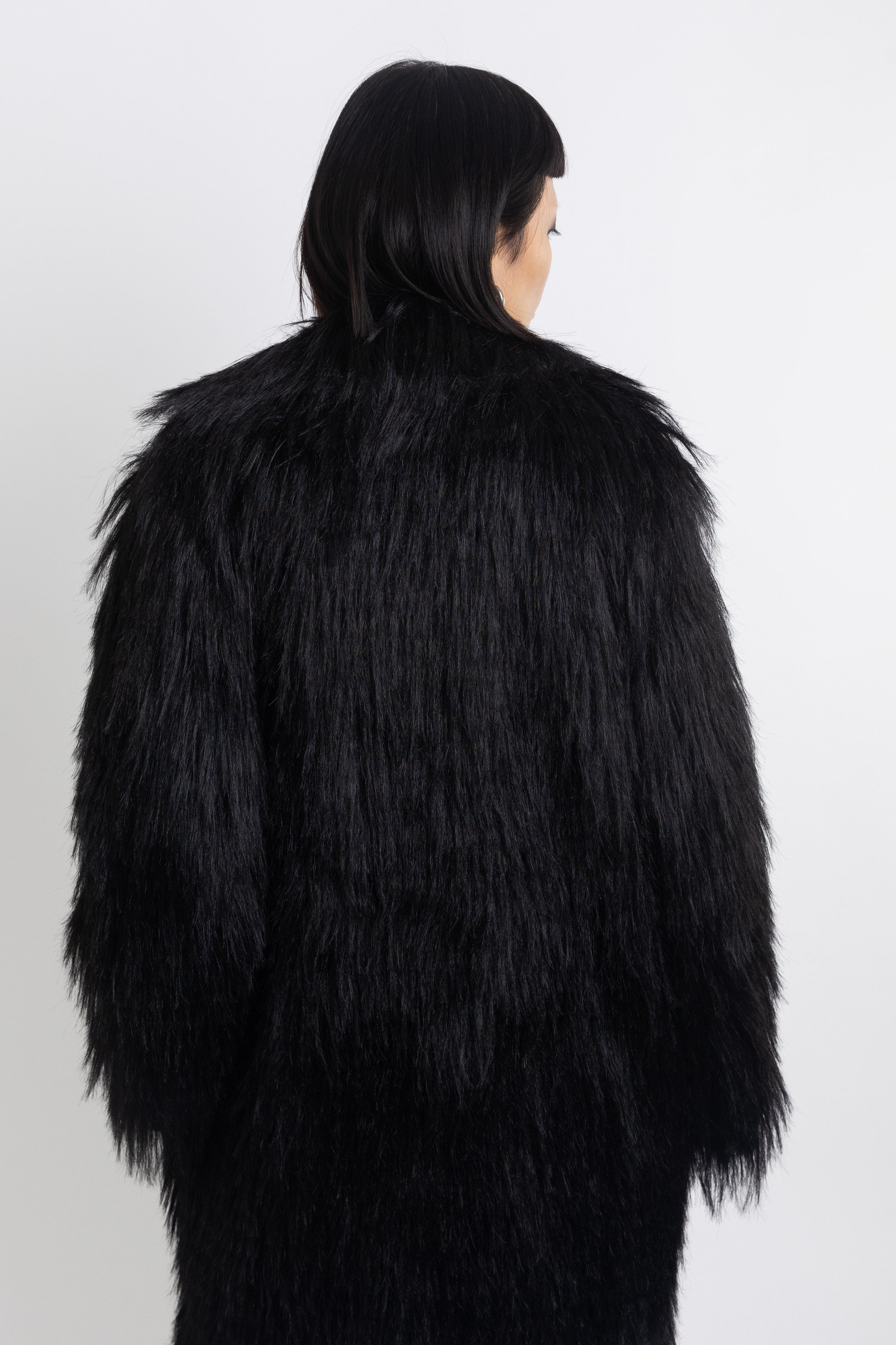 Longline black shaggy faux fur coat with silver horsebit clasps and shawl collar, worn by model