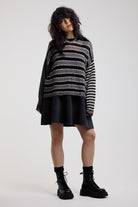 Black and white stripe oversized knit jumper with grunge distressed details, worn by model