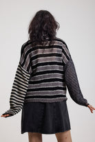 Back image of black and white stripe oversized knit jumper with grunge distressed details, worn by model