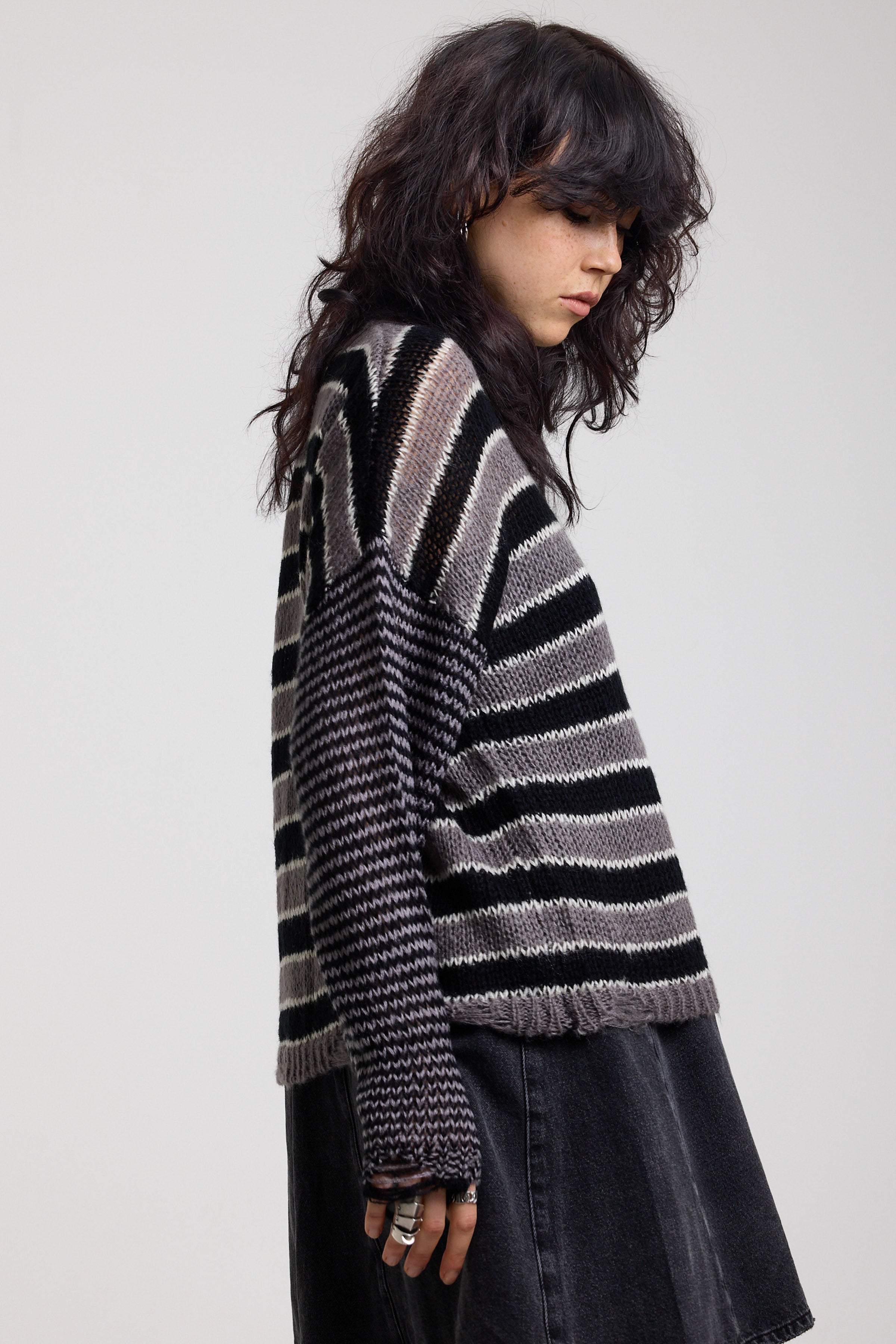 Side image of black and white stripe oversized knit jumper with grunge distressed details, worn by model