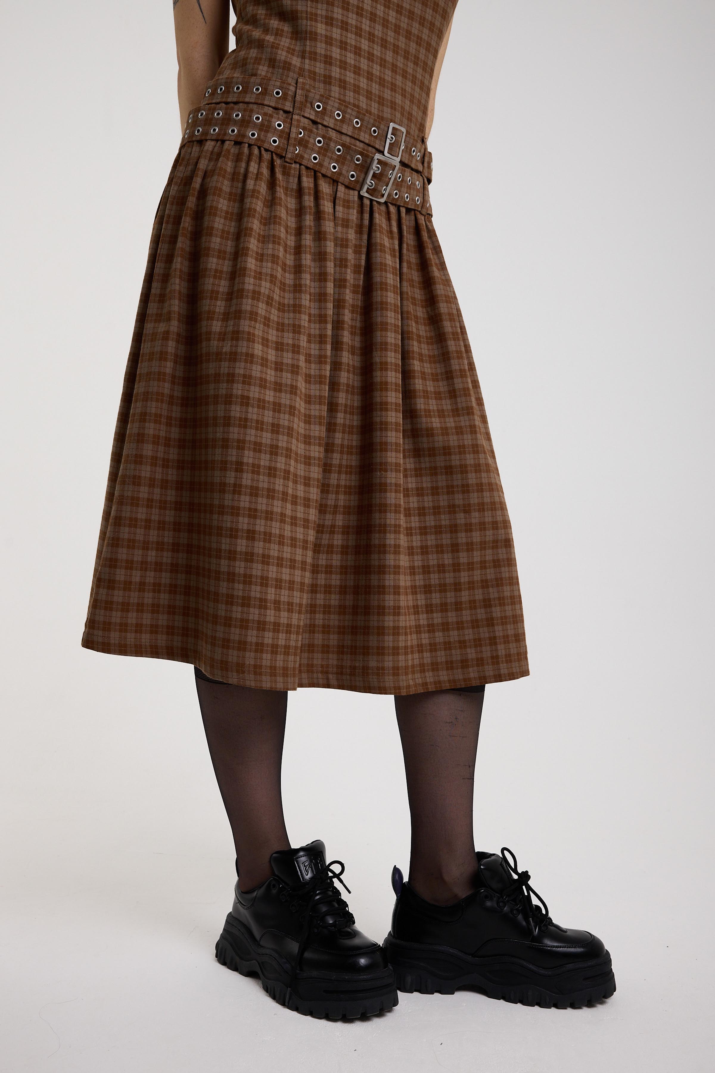 Close up of full skirt and double eyelet belt on brown tartan check midi dress, worn by model