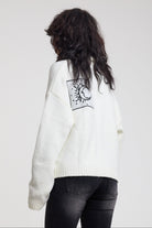 Back view of cream oversized knit with black moon patch detail, worn by model