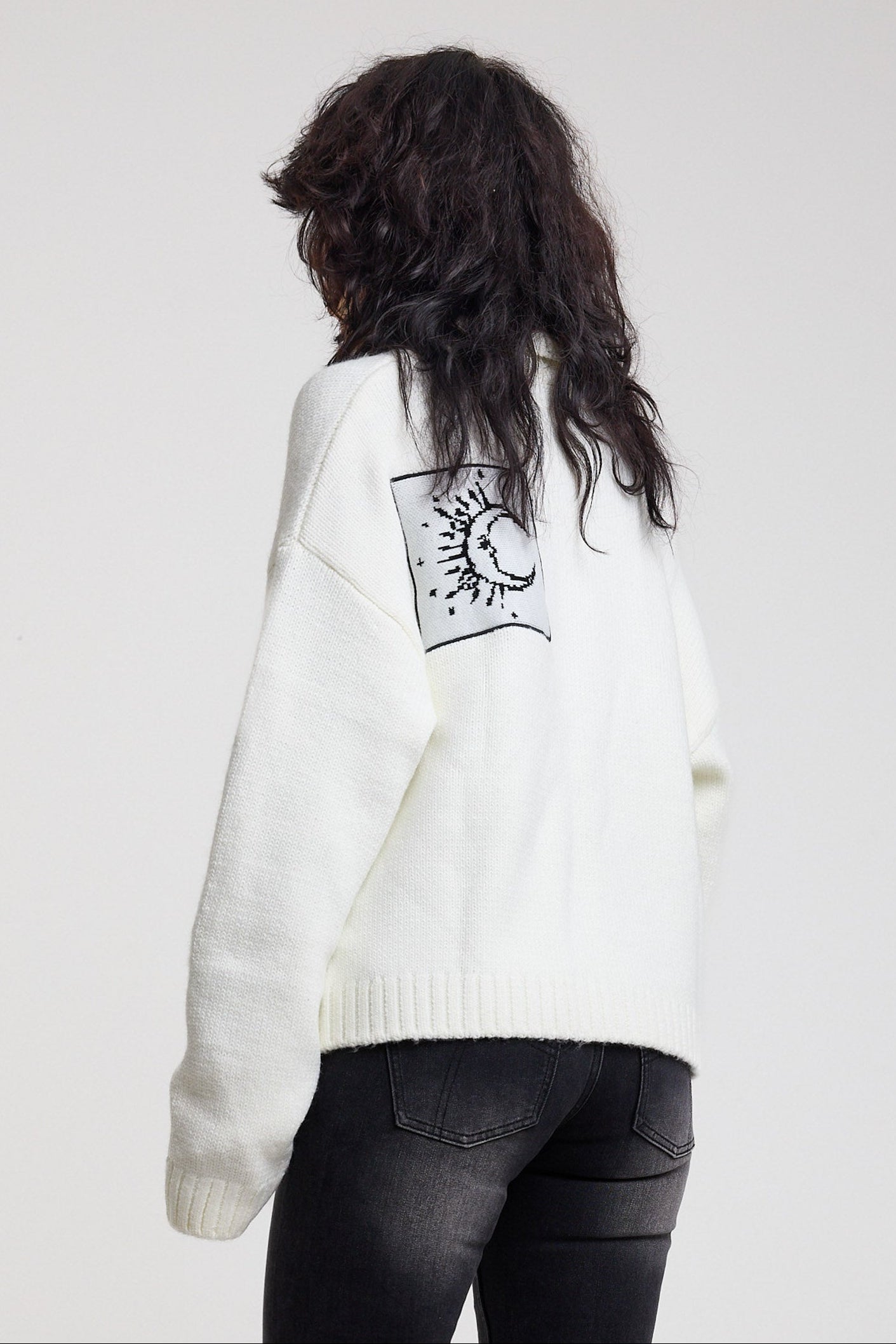 Back view of cream oversized knit with black moon patch detail, worn by model