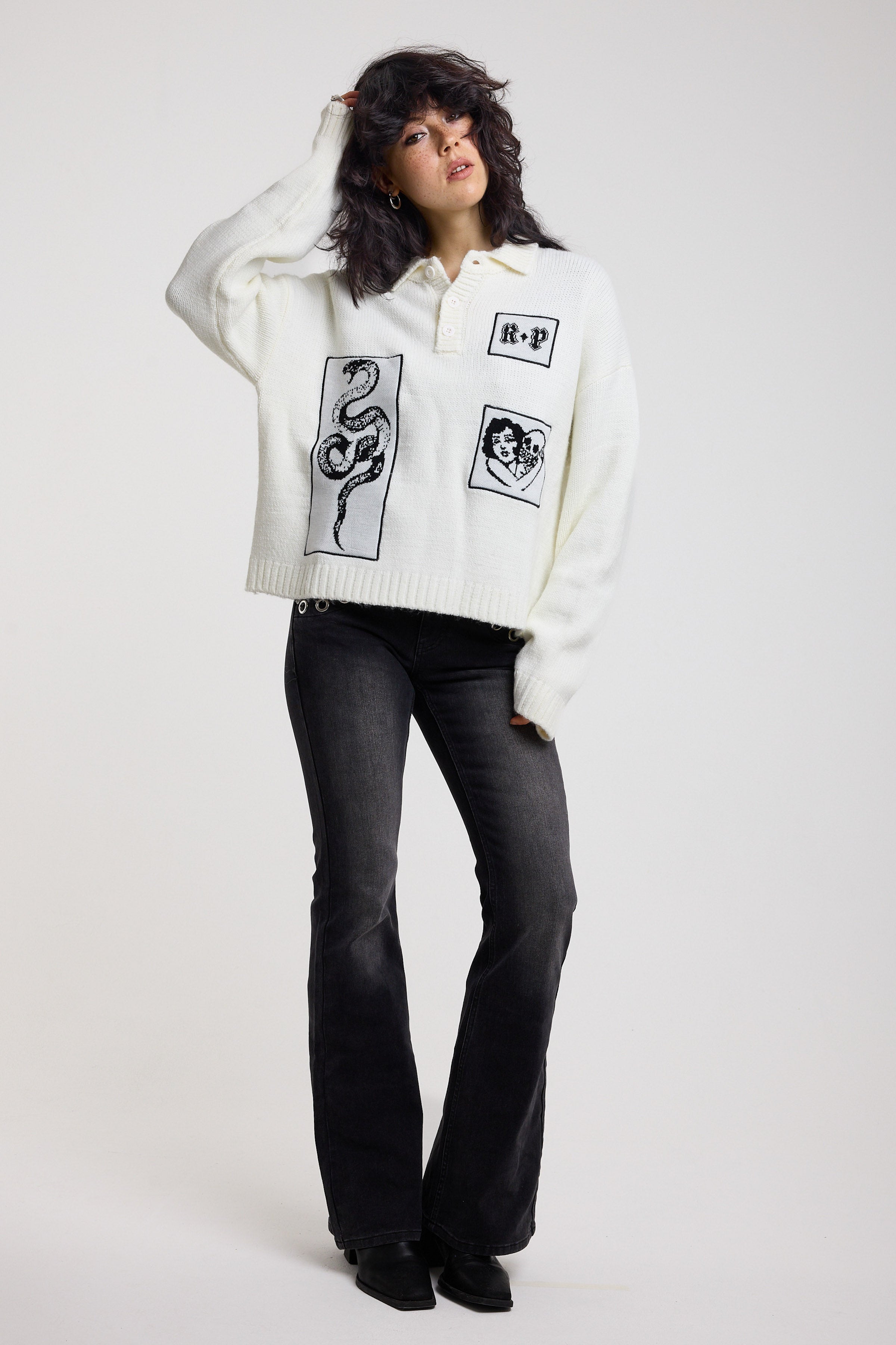 Cream oversized knit jumper with black graphic patch details and polo collar with black jeans, worn by model