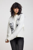 Cream oversized knit jumper with black graphic patch details and polo collar, worn by model