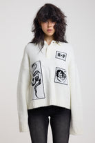 Cream oversized knit jumper with black graphic patch details and polo collar, worn by model