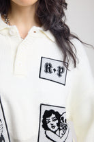 Close up of cream oversized knit jumper with black graphic patch details 