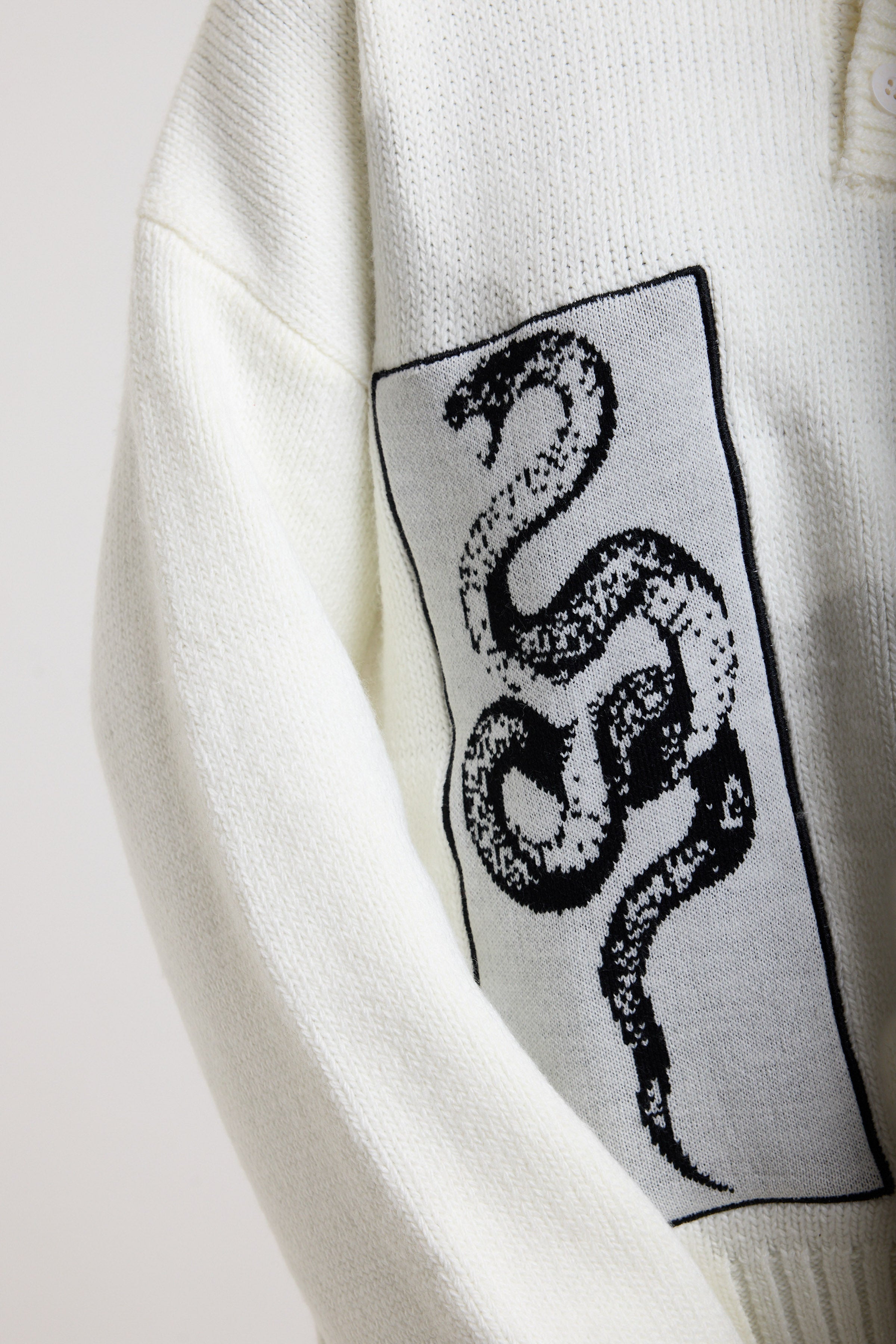 Close up of cream knit showing snake patch detail