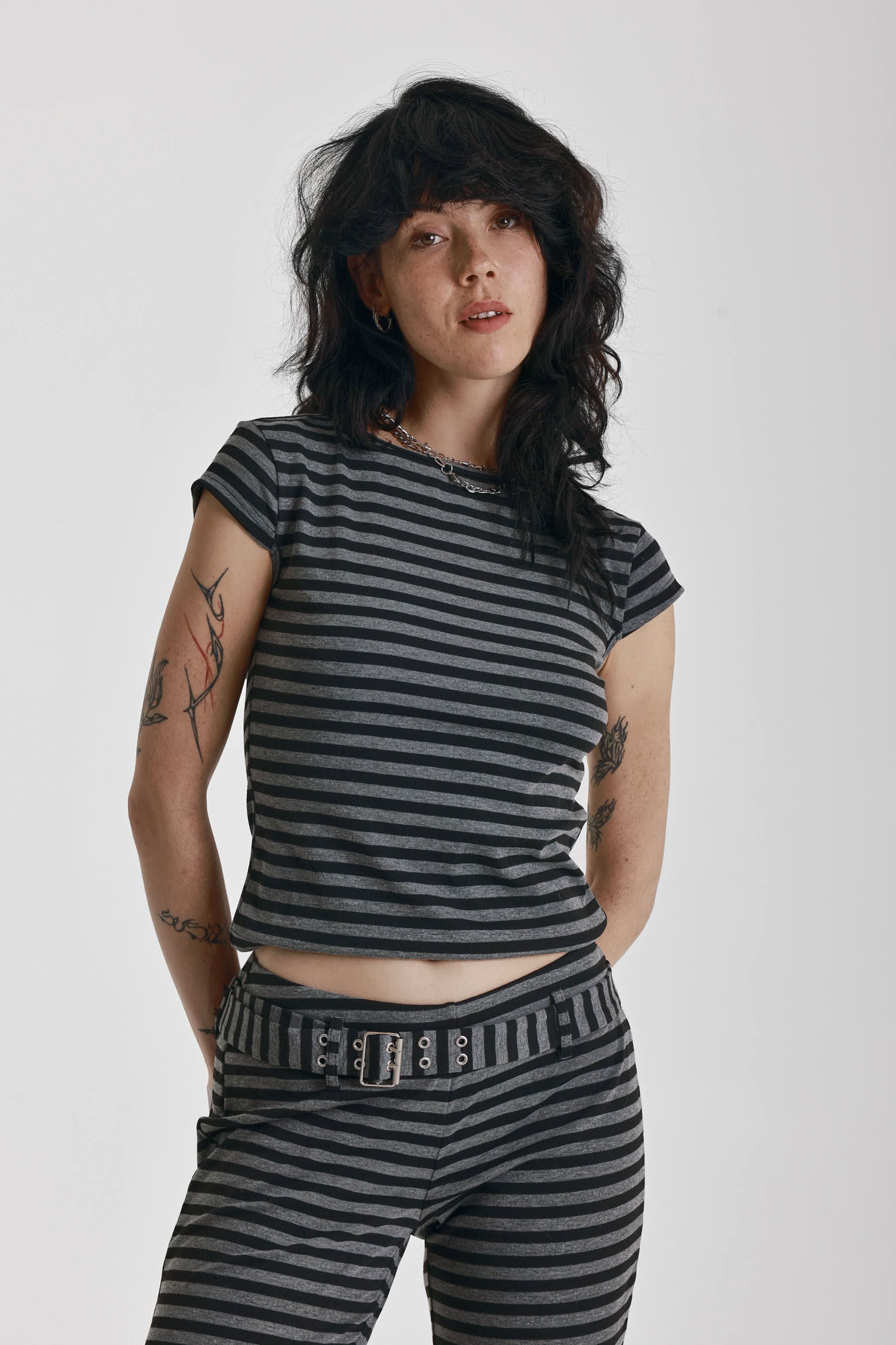 Grey and black stripe cap sleeve t-shirt with open back and eyelet buckle straps, worn by model