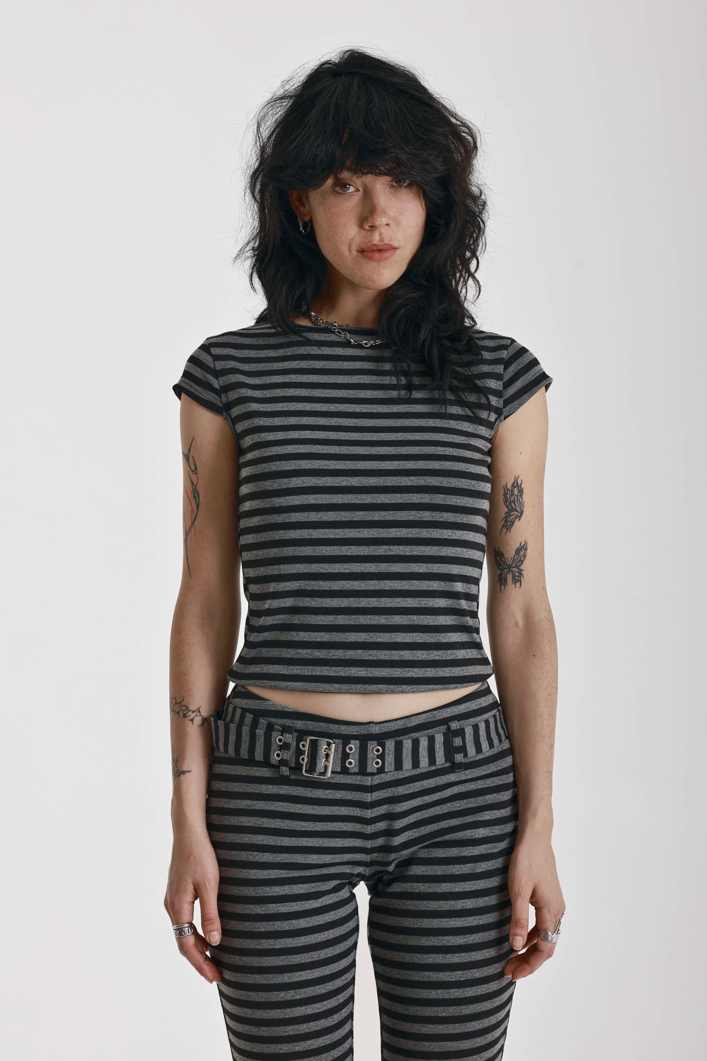 Grey and black stripe cap sleeve t-shirt with open back and eyelet buckle straps, worn by model