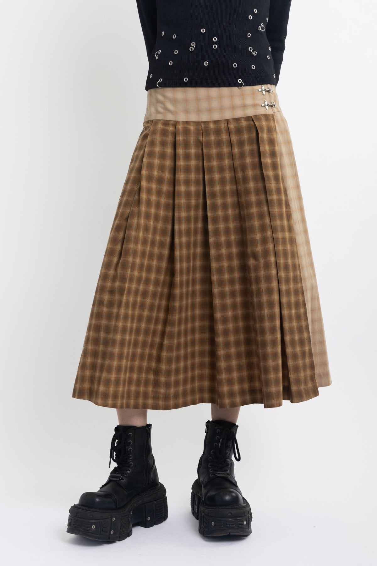 Spliced check pleated kilt midi skirt with silver clasp detail and thigh high split, worn by model