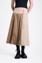 Beige and brown plaid pleated kilt maxi skirt with silver clasp detail and a wide waistband, worn by model