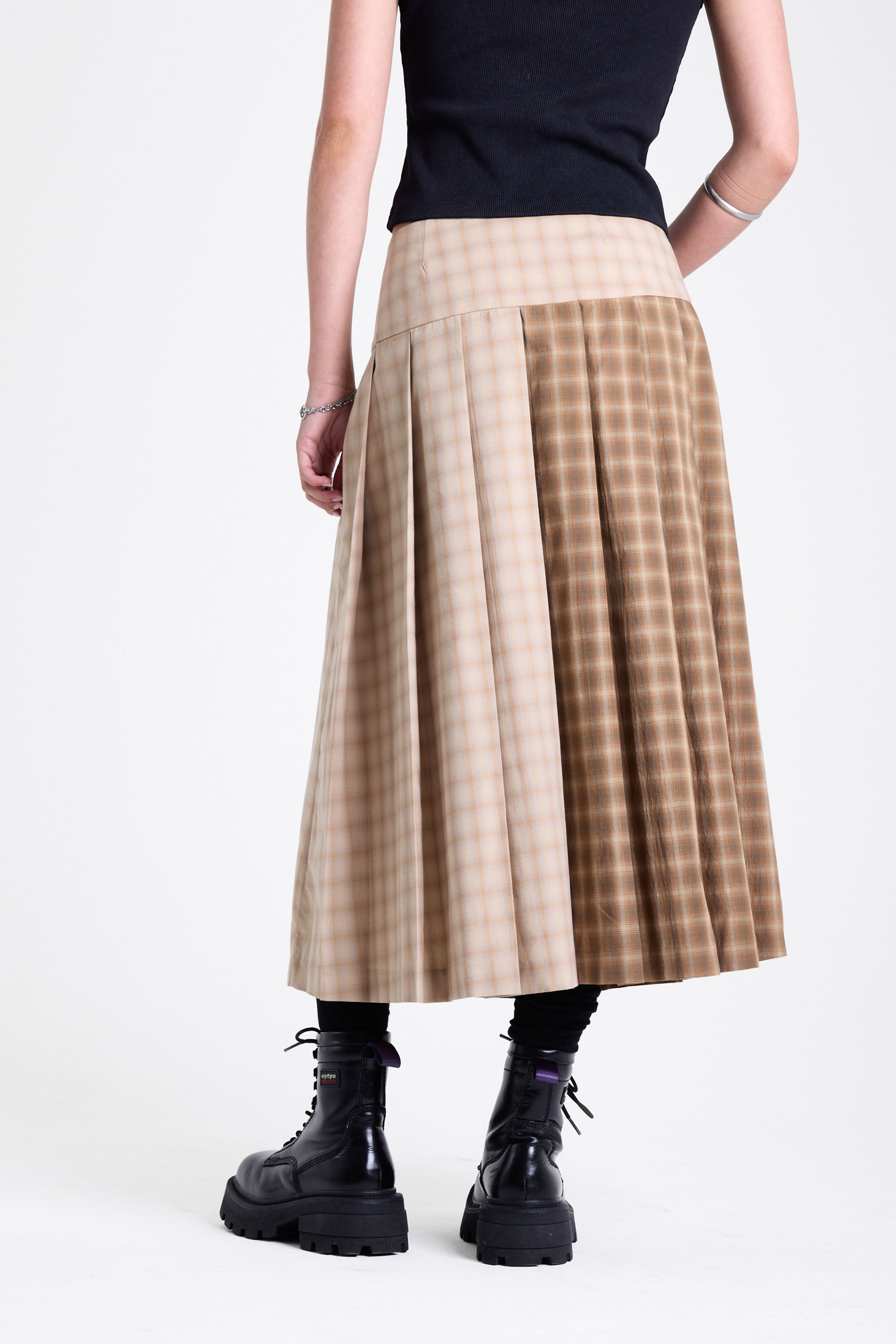 Beige and brown plaid pleated kilt maxi skirt with silver clasp detail and a wide waistband, worn by model