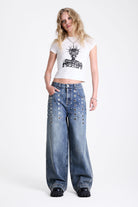 Vintage wash oversized baggy colossus jeans with silver eyelet and stud hardware detail, worn by model